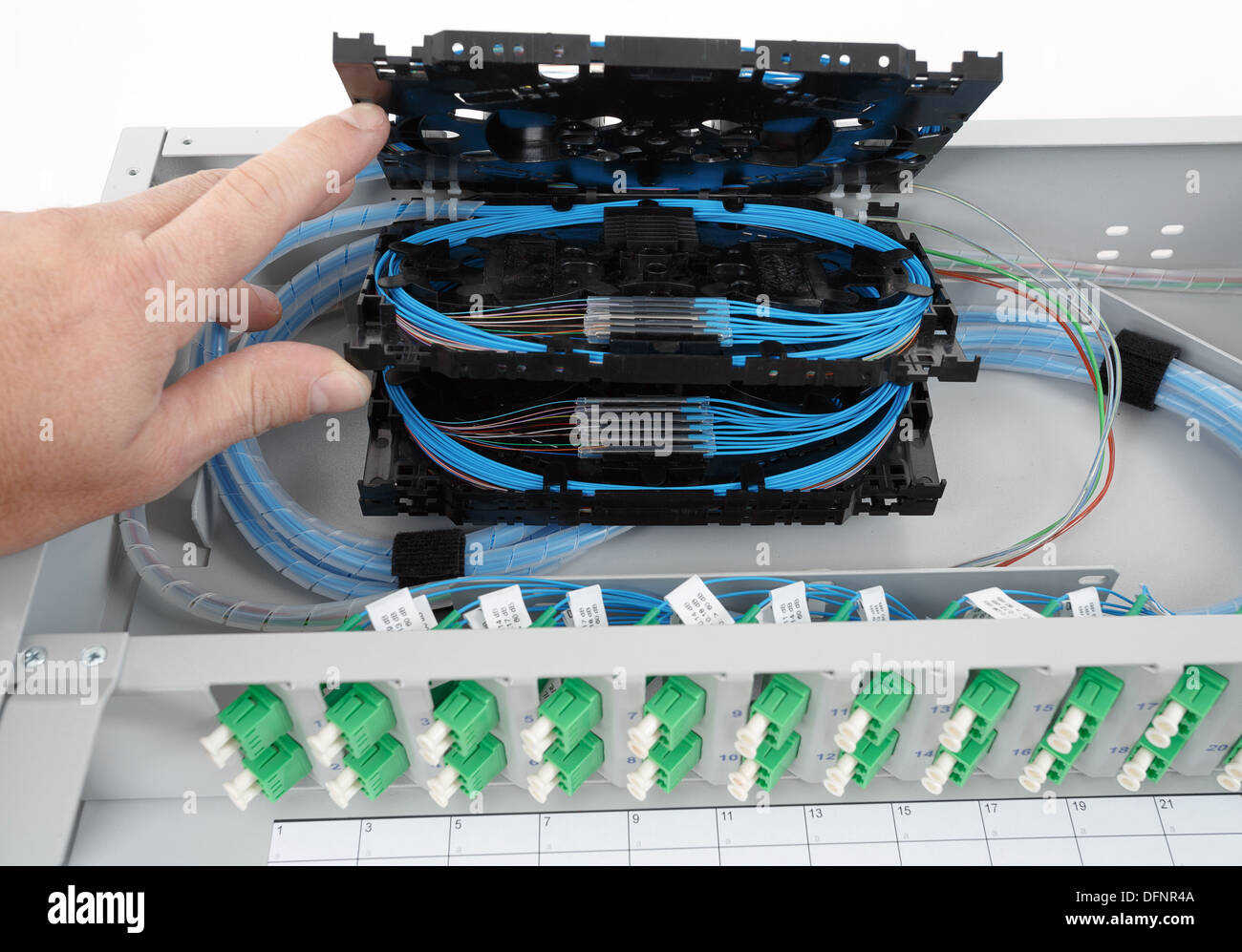stack of fiber optic splice cassettes with protection sleeve and blue fibres installed in optical distribution frame Stock Photo