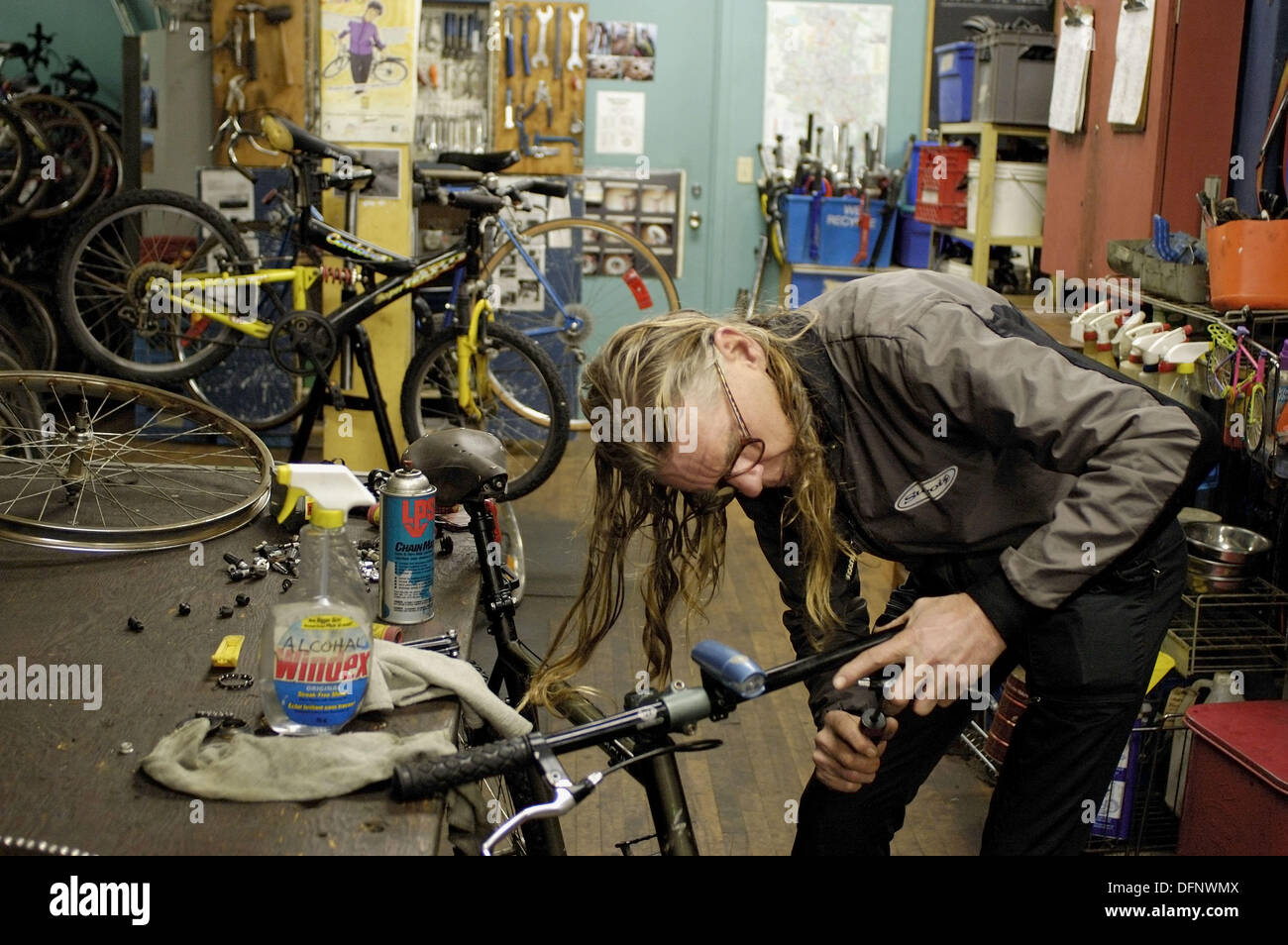 Canada, Ontario, Kitchener. An long haired, older male volunteer fixes a  bike handle bar at Recycle Cycles Stock Photo - Alamy