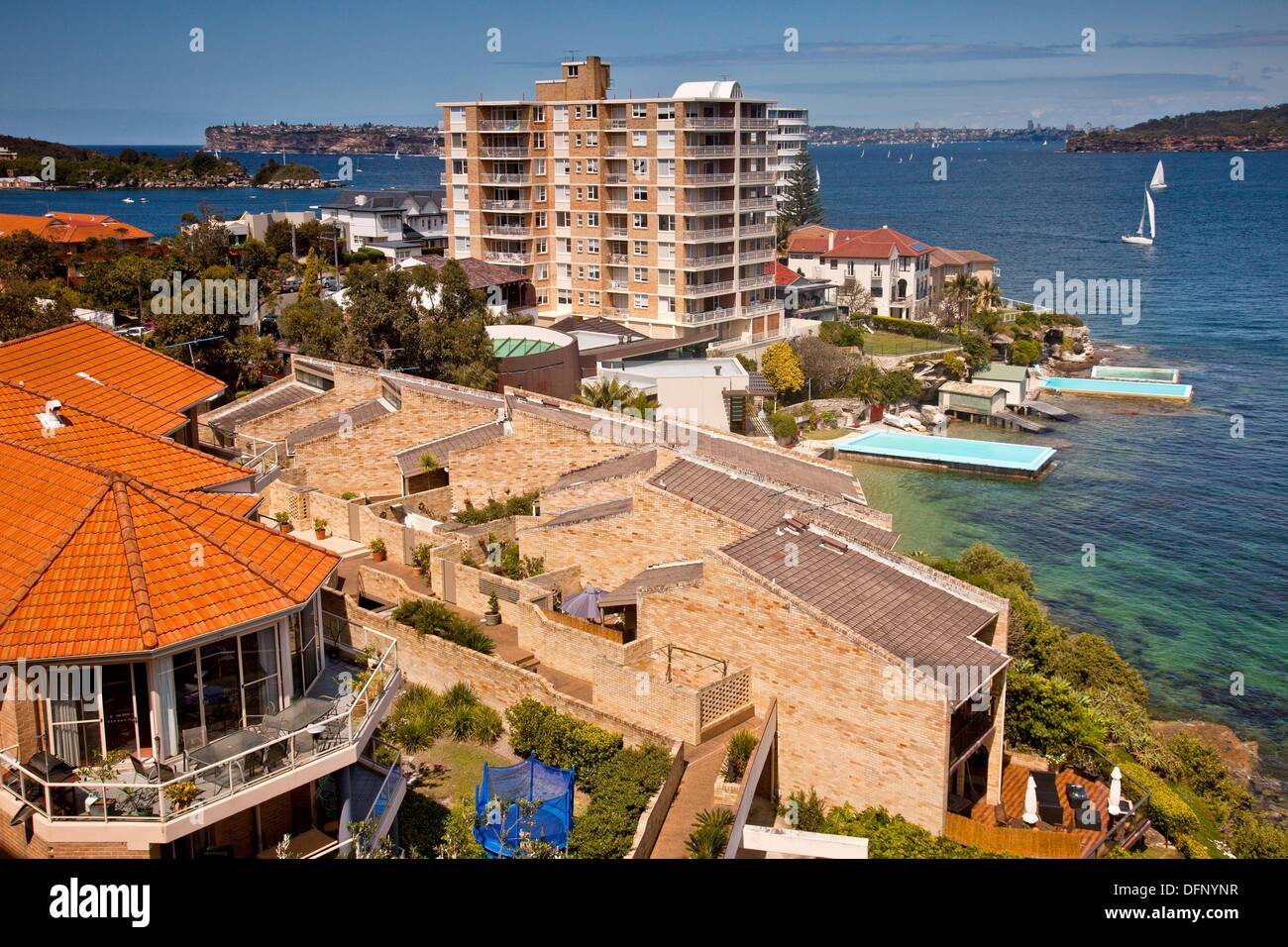 Yachts cruise into Manly harbour, typical Manly waterfront homes and