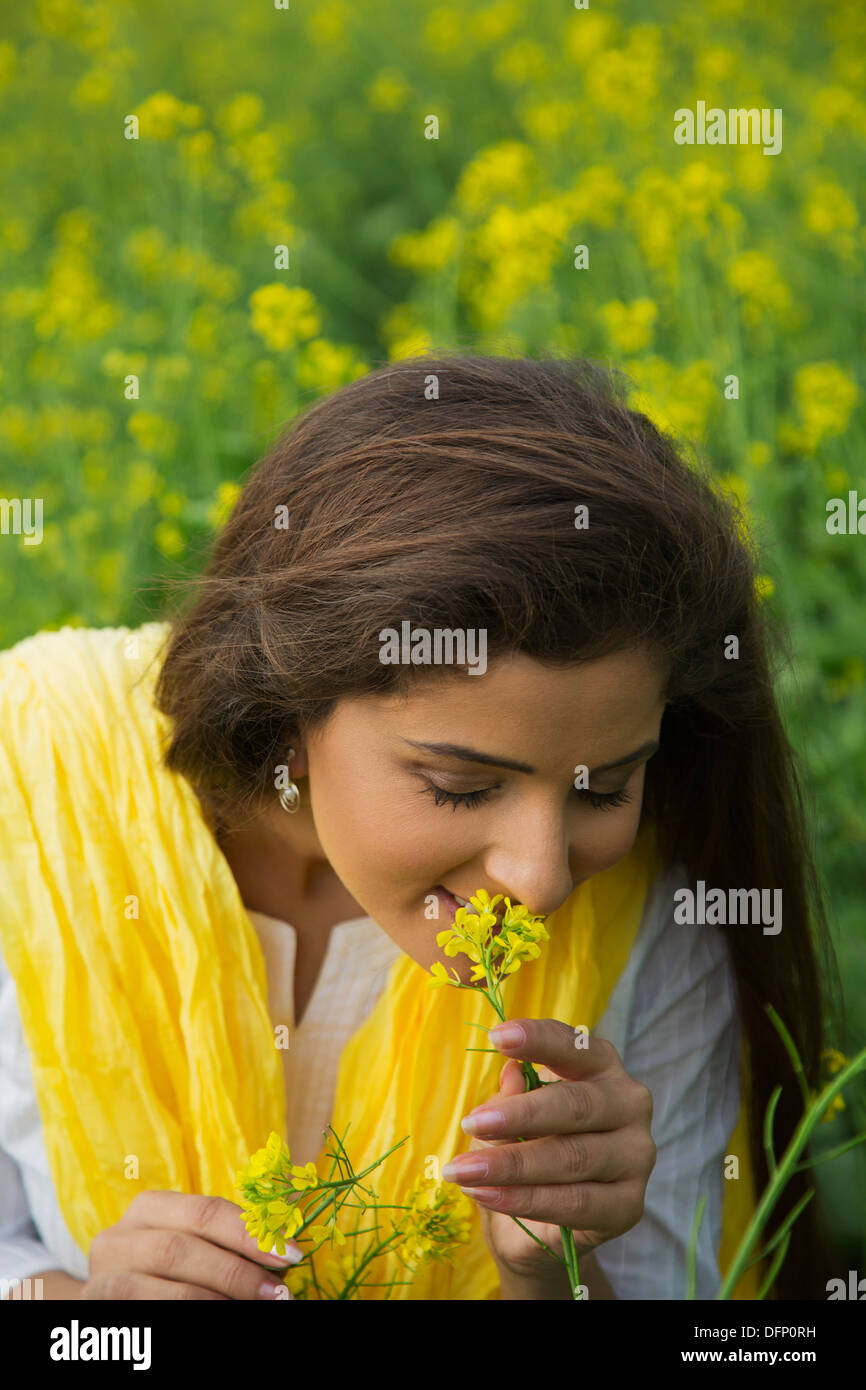 Close-up of a woman smelling flower in a mustard field Stock Photo