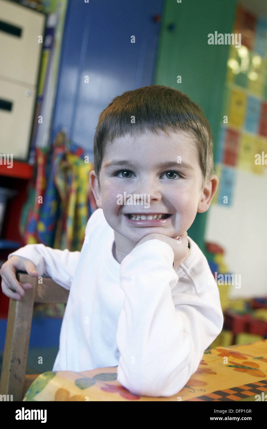3 year old boy looking off camera at nursery,smiling, chin on his hand