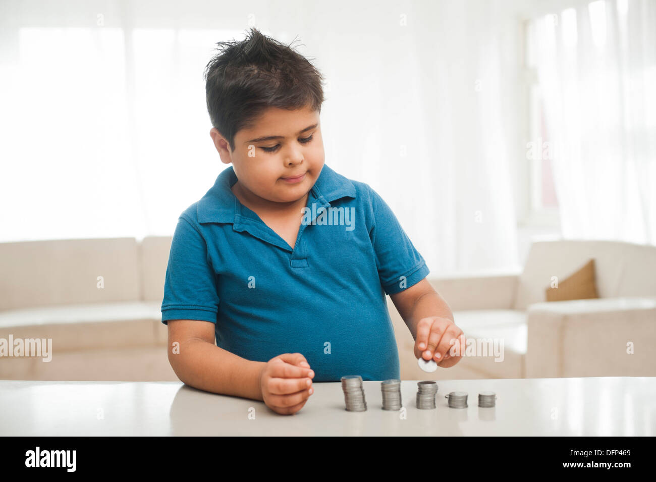 Boy making a stack of coins Stock Photo - Alamy