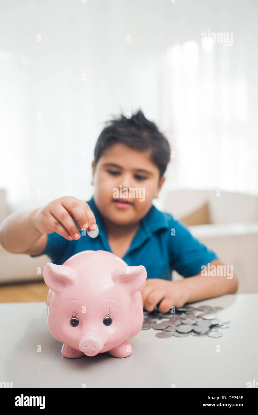 Boy inserting coin into a piggy bank Stock Photo - Alamy
