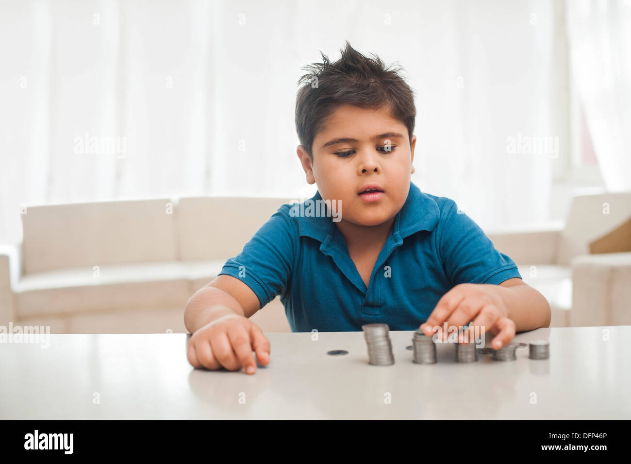 Boy making a stack of coins Stock Photo - Alamy