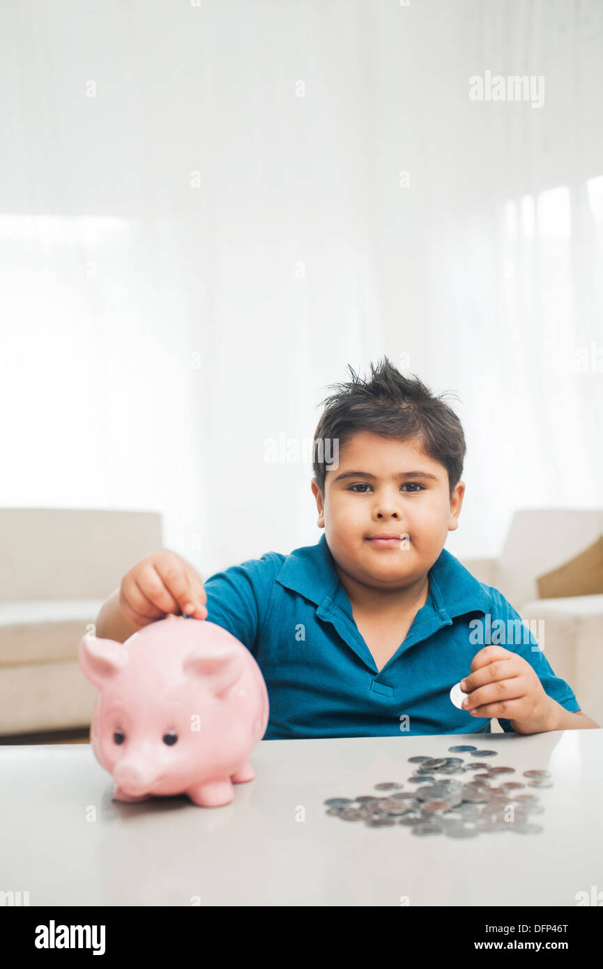 Boy inserting coin into a piggy bank Stock Photo - Alamy