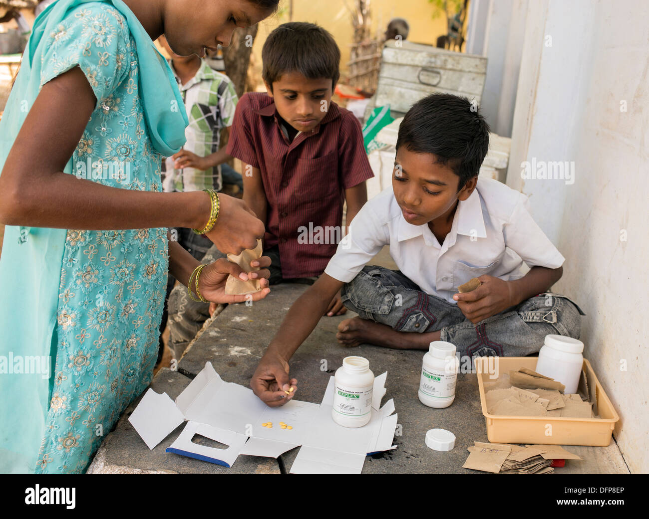 Indian children putting vitamin B tablets into packets at Sri Sathya Sai Baba mobile outreach hospital pharmacy. India Stock Photo