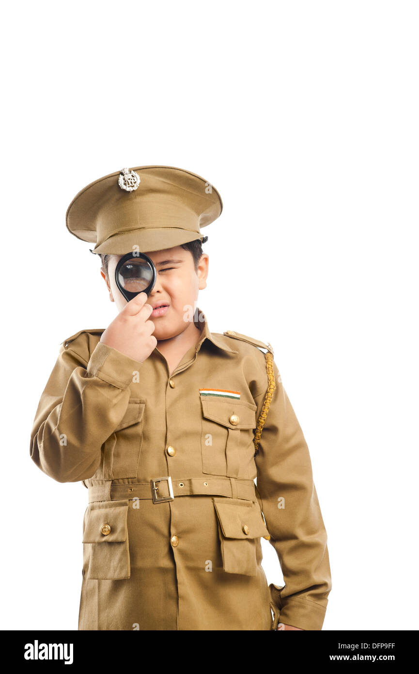 Close-up of a boy dressed as a police uniform looking through a magnifying glass Stock Photo