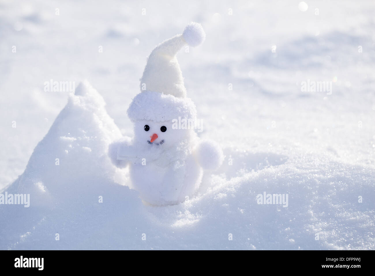 Little funny snowman near bank of snow. Stock Photo