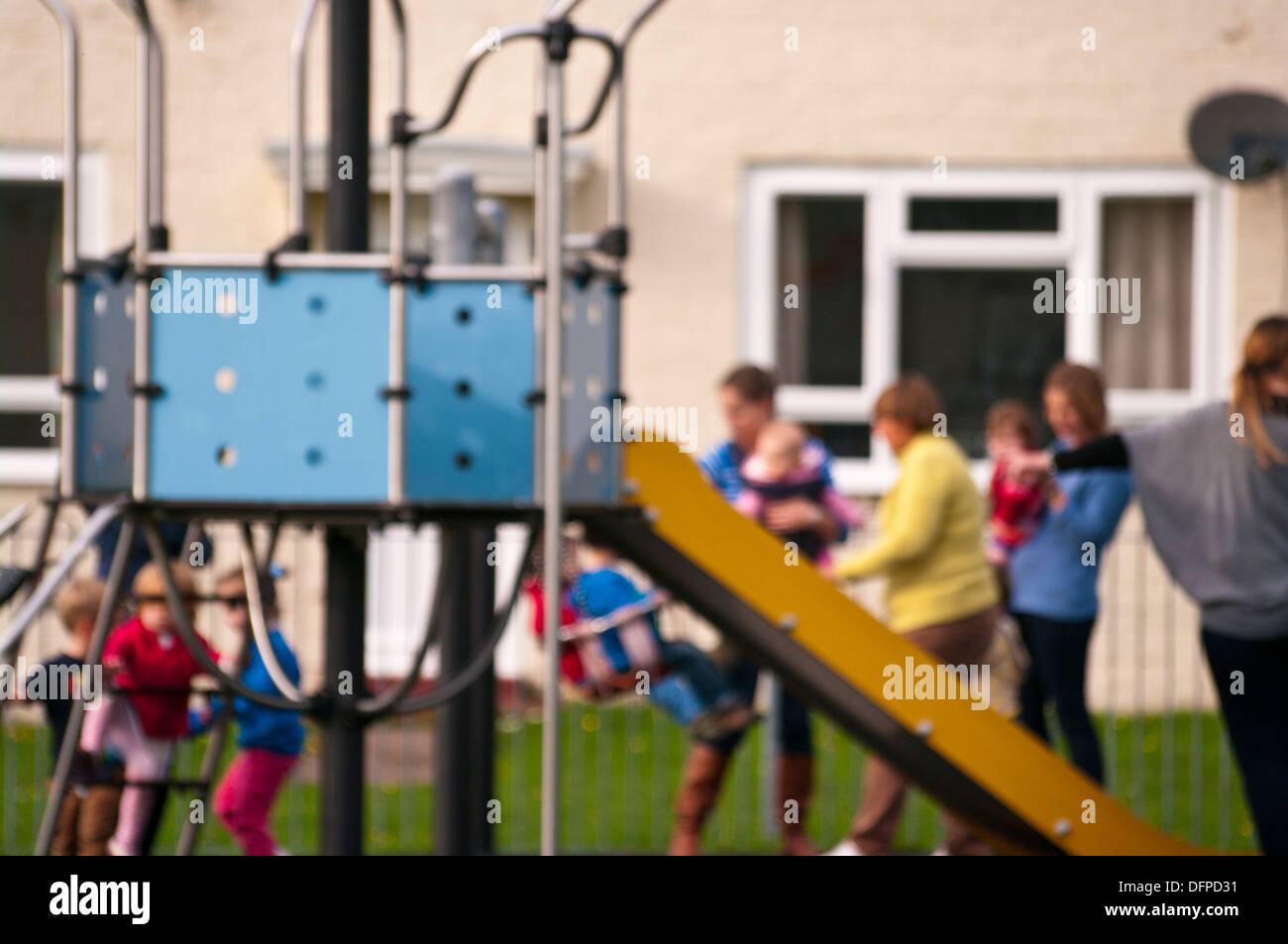 parents and children at a childrens playground (intentionally out of focus to conceal subjects identities) Stock Photo