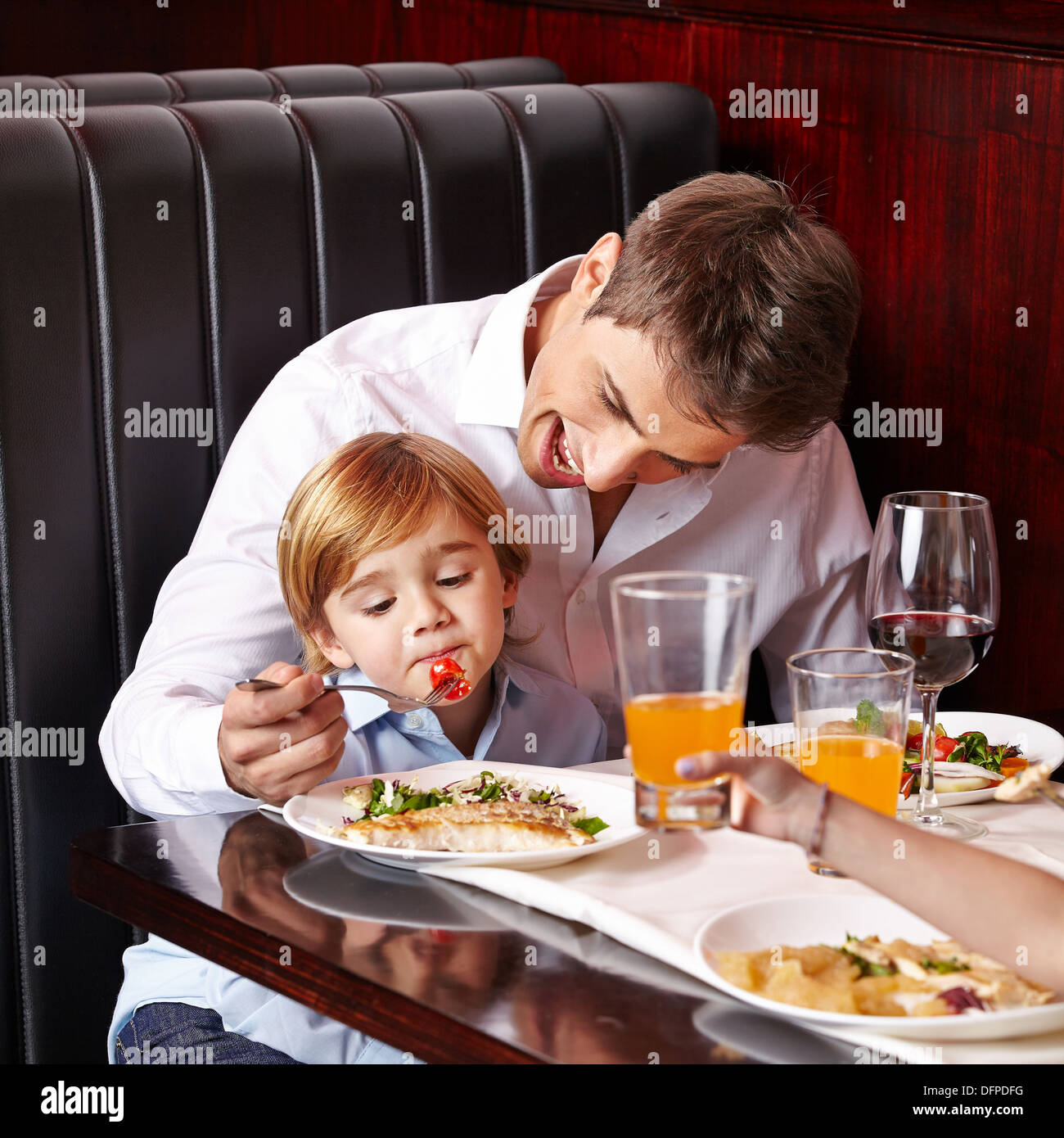 Child is a picky eater in restaurant and father tries to feed it Stock Photo