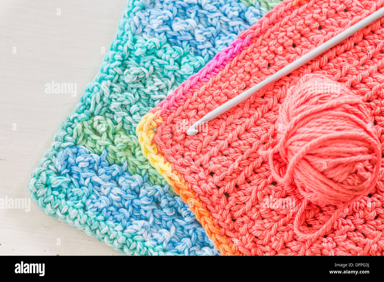 Two hand crotched dishcloths with a crotchet hook and ball of yarn. Stock Photo