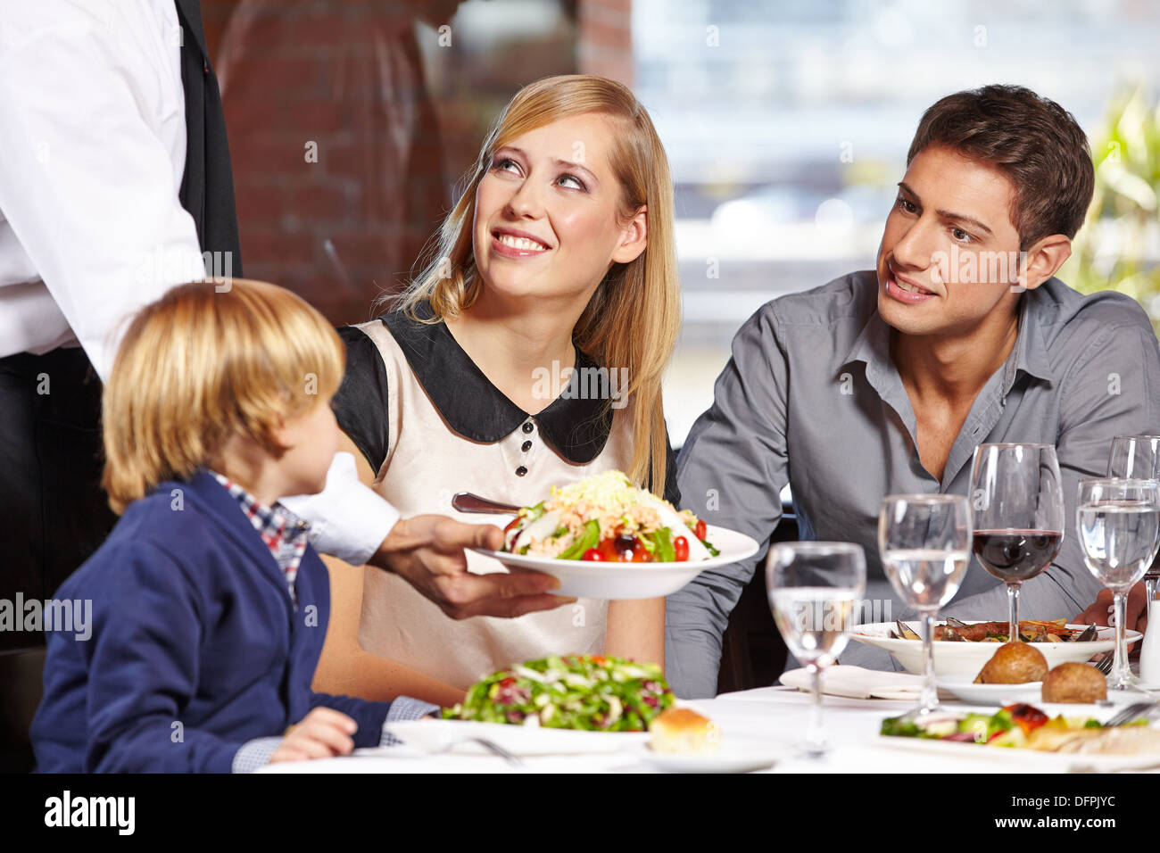 Waiter serving a family in a restaurant and bringing a full plate Stock Photo
