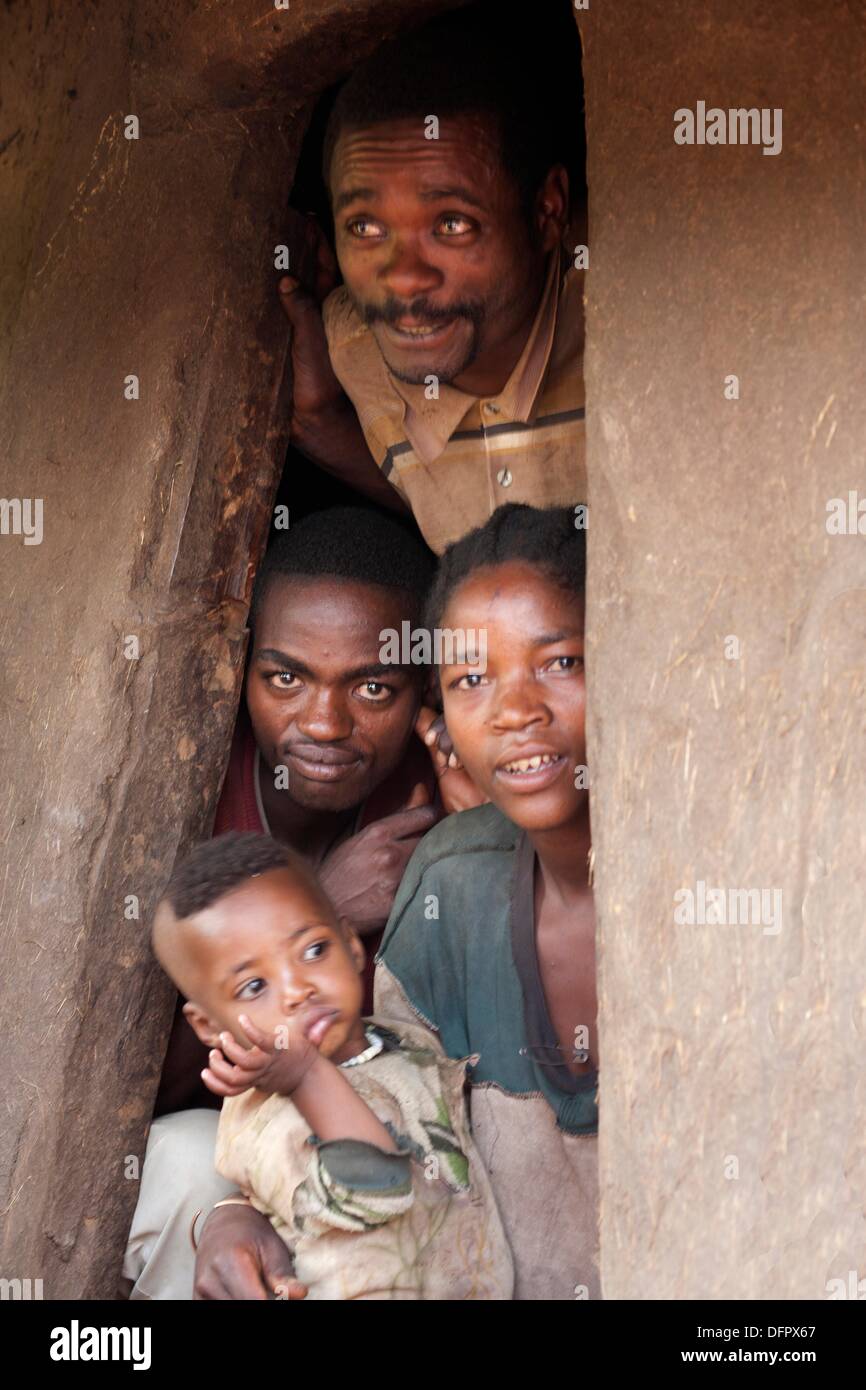Bench tribe family looking out of the entrance to their traditional hut, Ethiopia, East Africa. Stock Photo