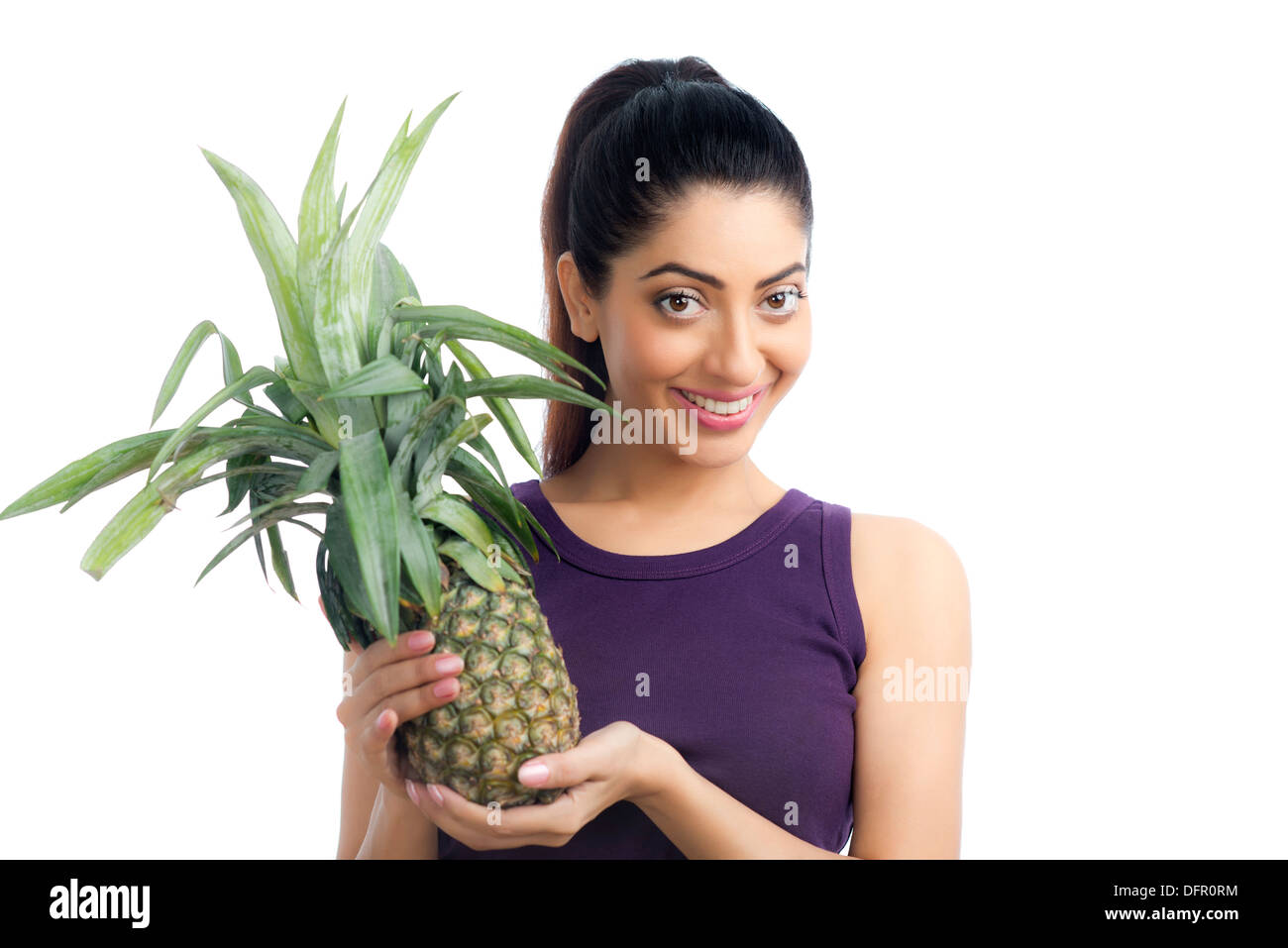 Portrait of a woman holding a pineapple and smiling Stock Photo
