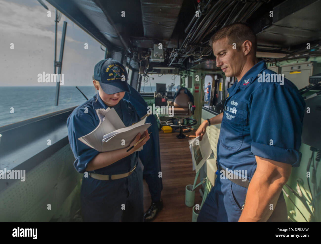 Mass Communication Specialist 2nd Class Gary Granger gives photos to be released to Lt. j.g. Sidney Cheek on the bridge of the amphibious transport dock USS New Orleans (LPD 18). New Orleans is currently deployed in the U.S. 7th Fleet area of responsibili Stock Photo