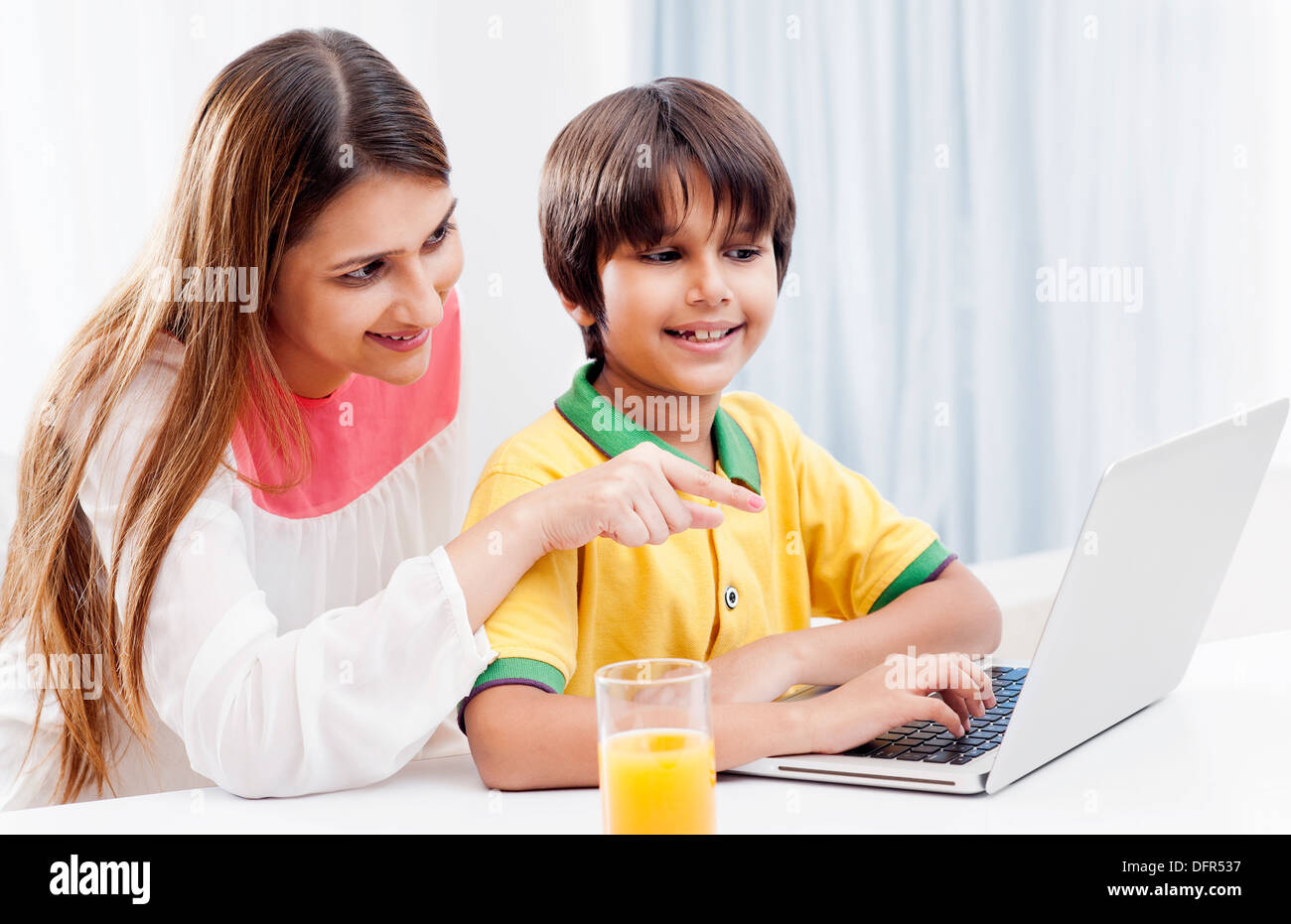 Boy using a laptop with his mother sitting behind him Stock Photo