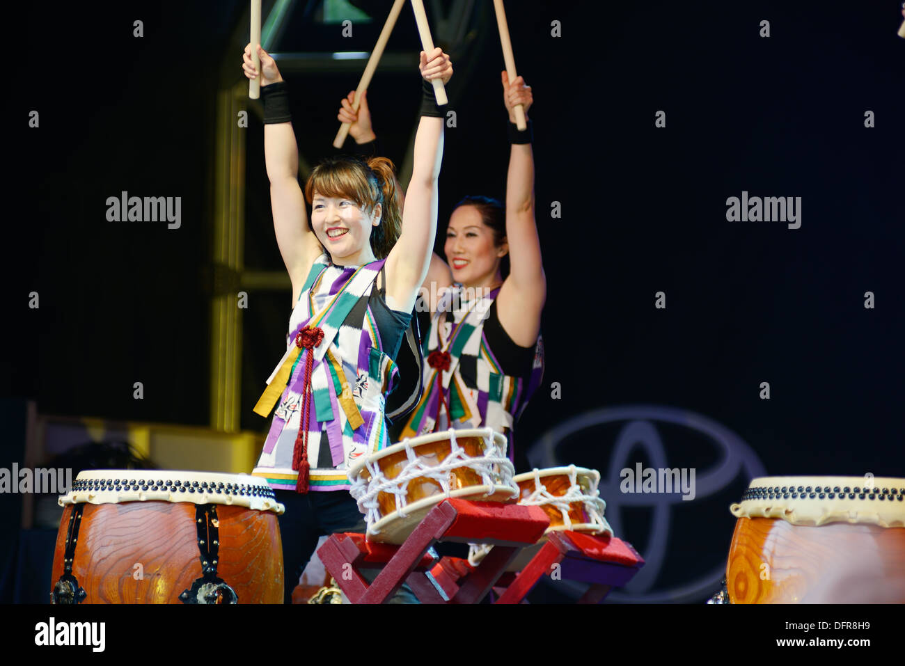 Japanese taiko drummers are female. Two people enjoying performance of music at matsuri in London. Saturday 5th October 2013 Stock Photo