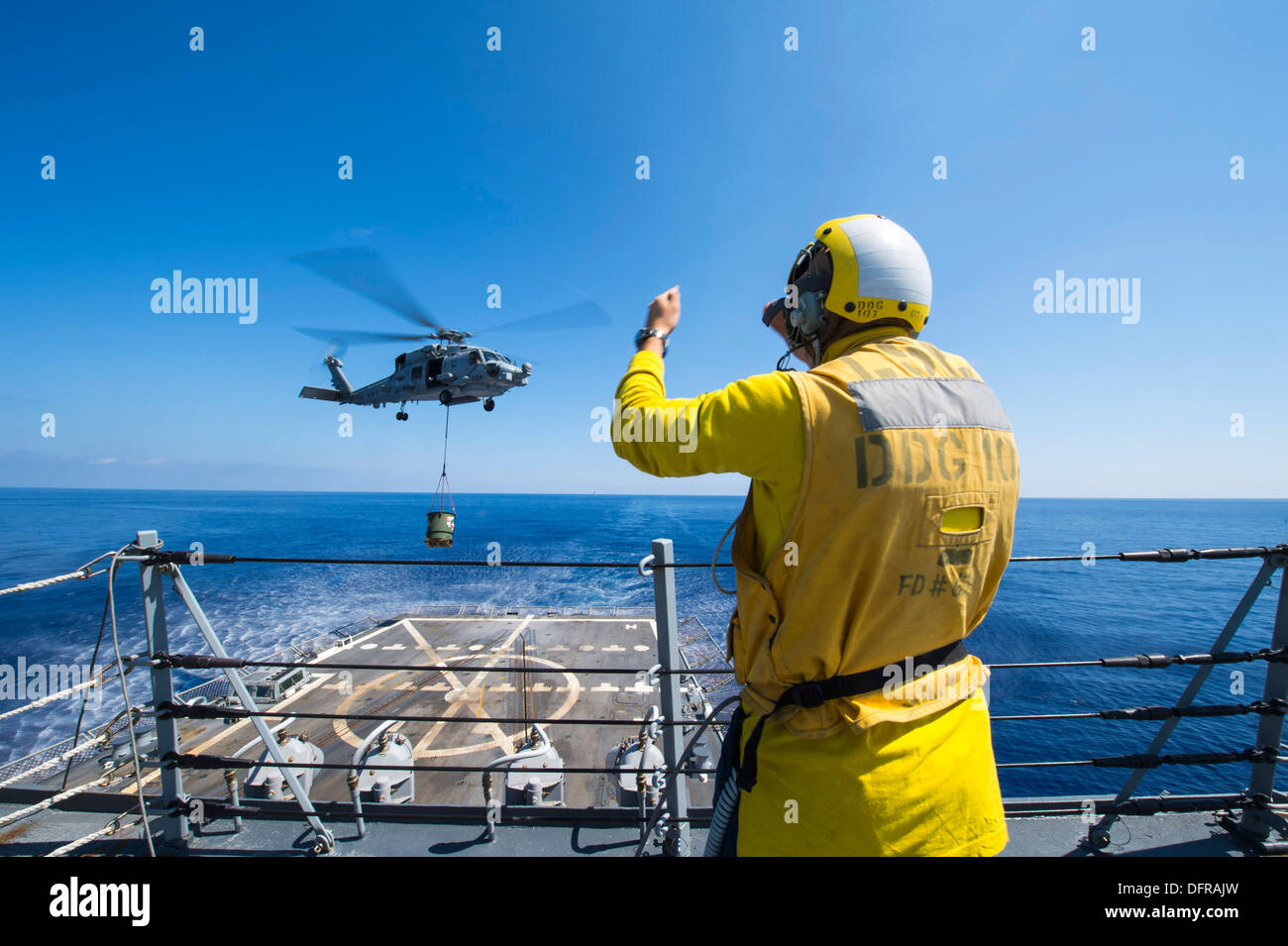Boatswain's Mate 3rd Class Taylor Baxley signals a SH60R Seahawk to the flight deck to deliver