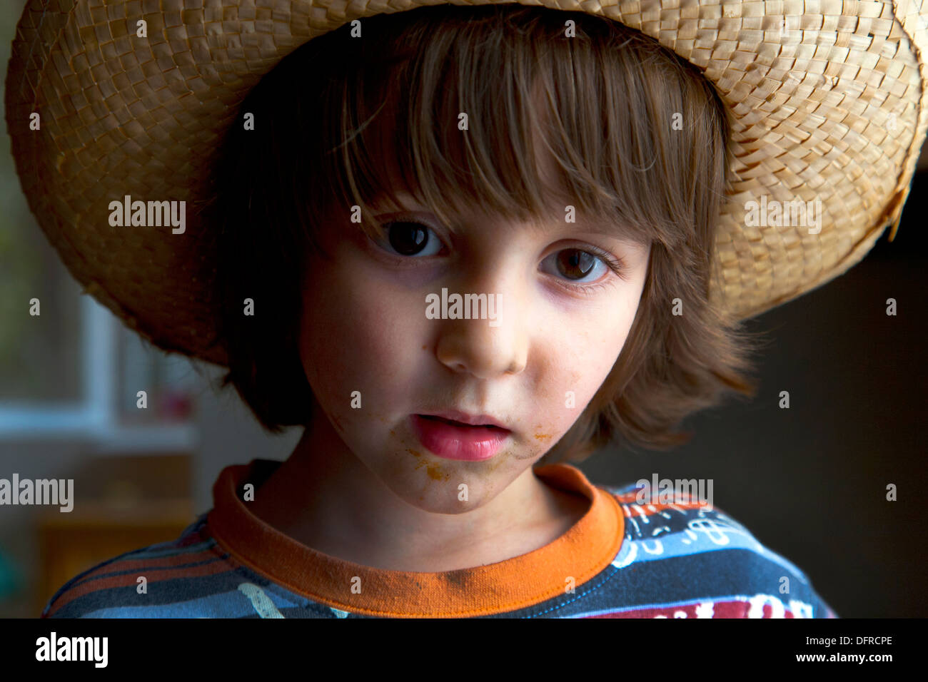 Cute four and a half year old boy wearing a wicker hat. Stock Photo