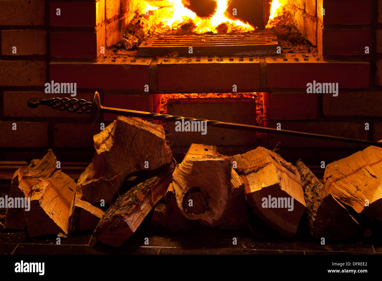 poker, firewood and near fireplace in evening time Stock Photo