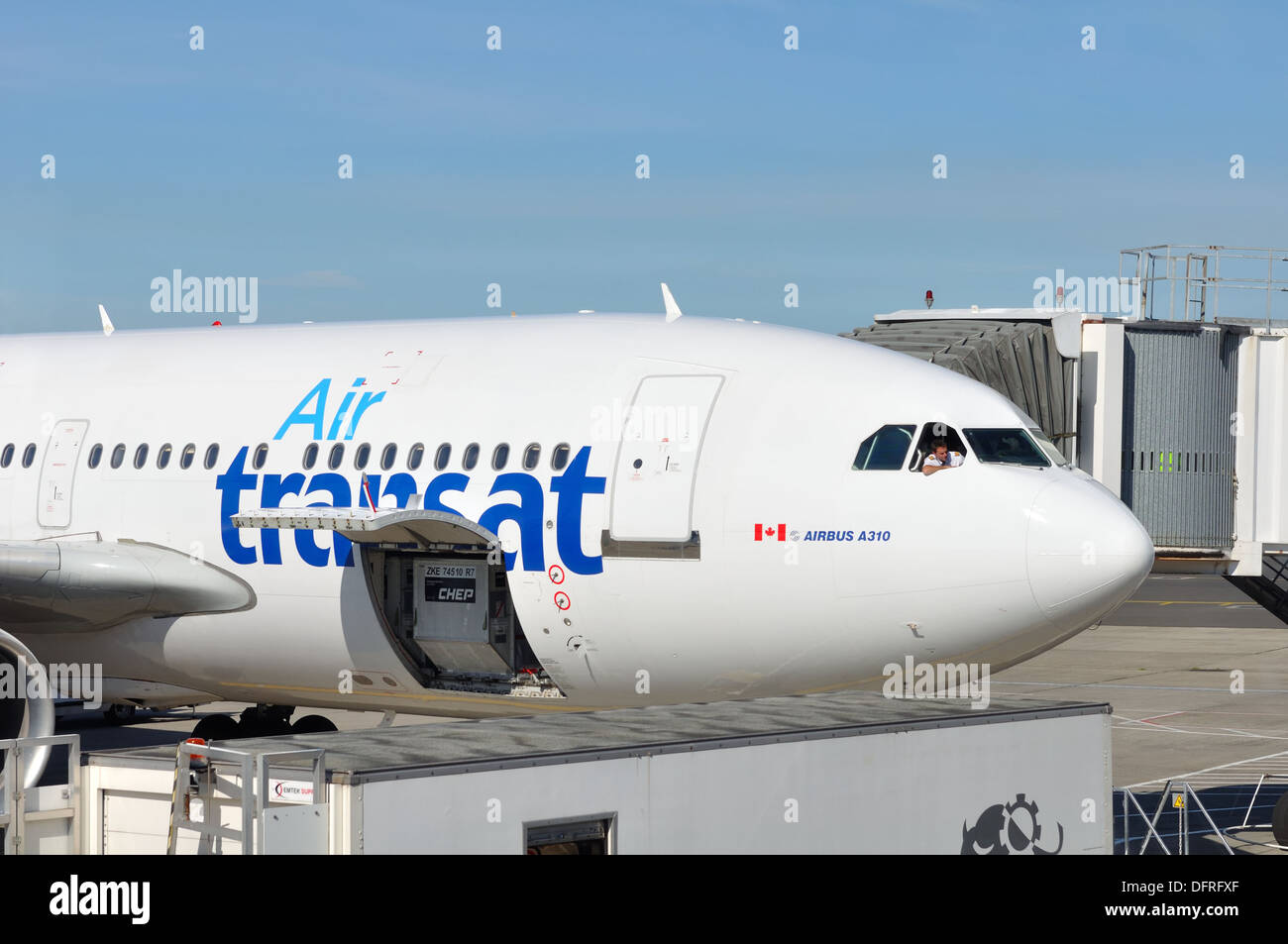 Air Transat airbus being loaded whilst pilot looks on leaning out from cockpit window. Stock Photo