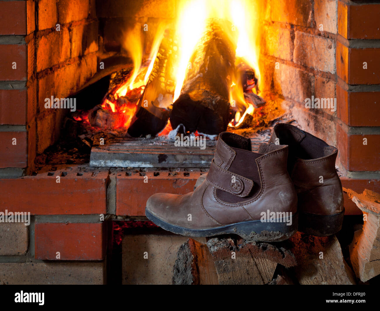 boots are dried near fire in fireplace in evening time Stock Photo