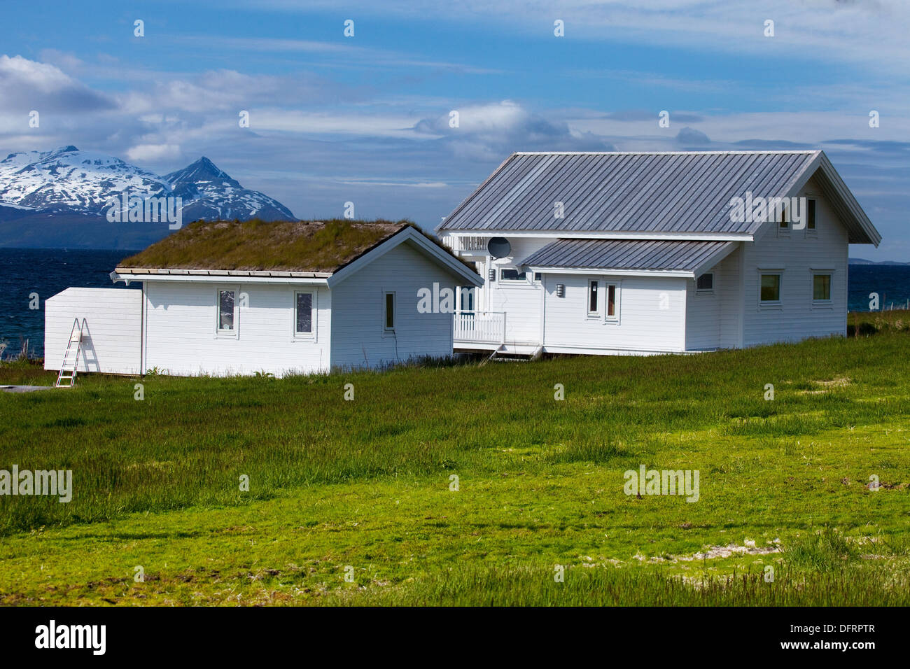 Houses with the traditional grass roof overlooking a fjord and snowy mountains in Lyngen Peninsula, Troms county, Norway, Europe Stock Photo