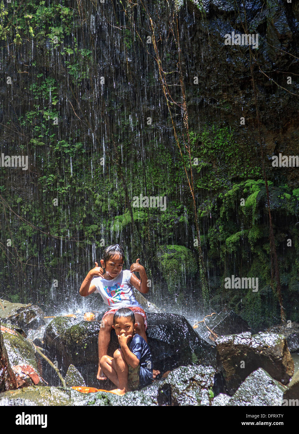 Young children play in cascading spray of Yekula waterfall on the island of Kosrae, Micronesia. Stock Photo