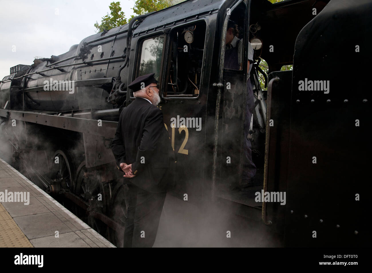 The station master talks to the engine driver of a steam train on the Blue Bell Railway heritage line platform. Stock Photo