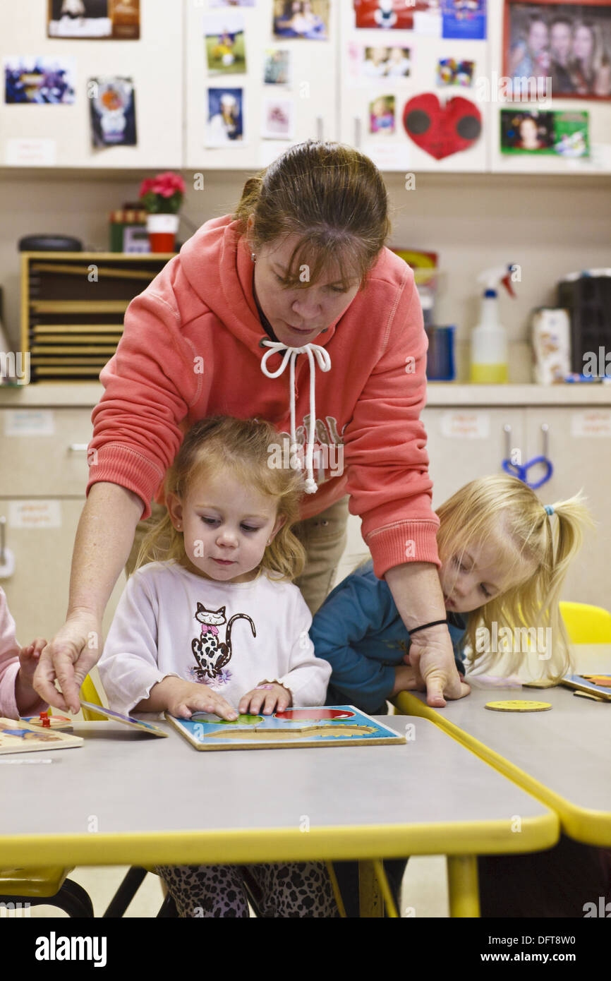 Teacher and children students work puzzles in daycare facility Stock