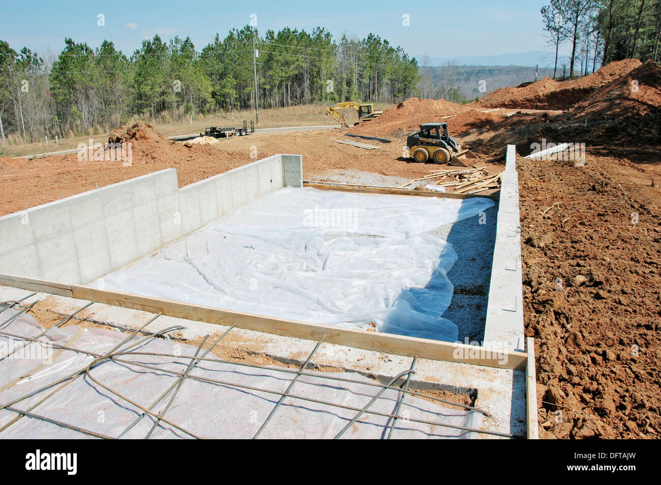 Bobcat dirt work around new foundation for new home construction Stock