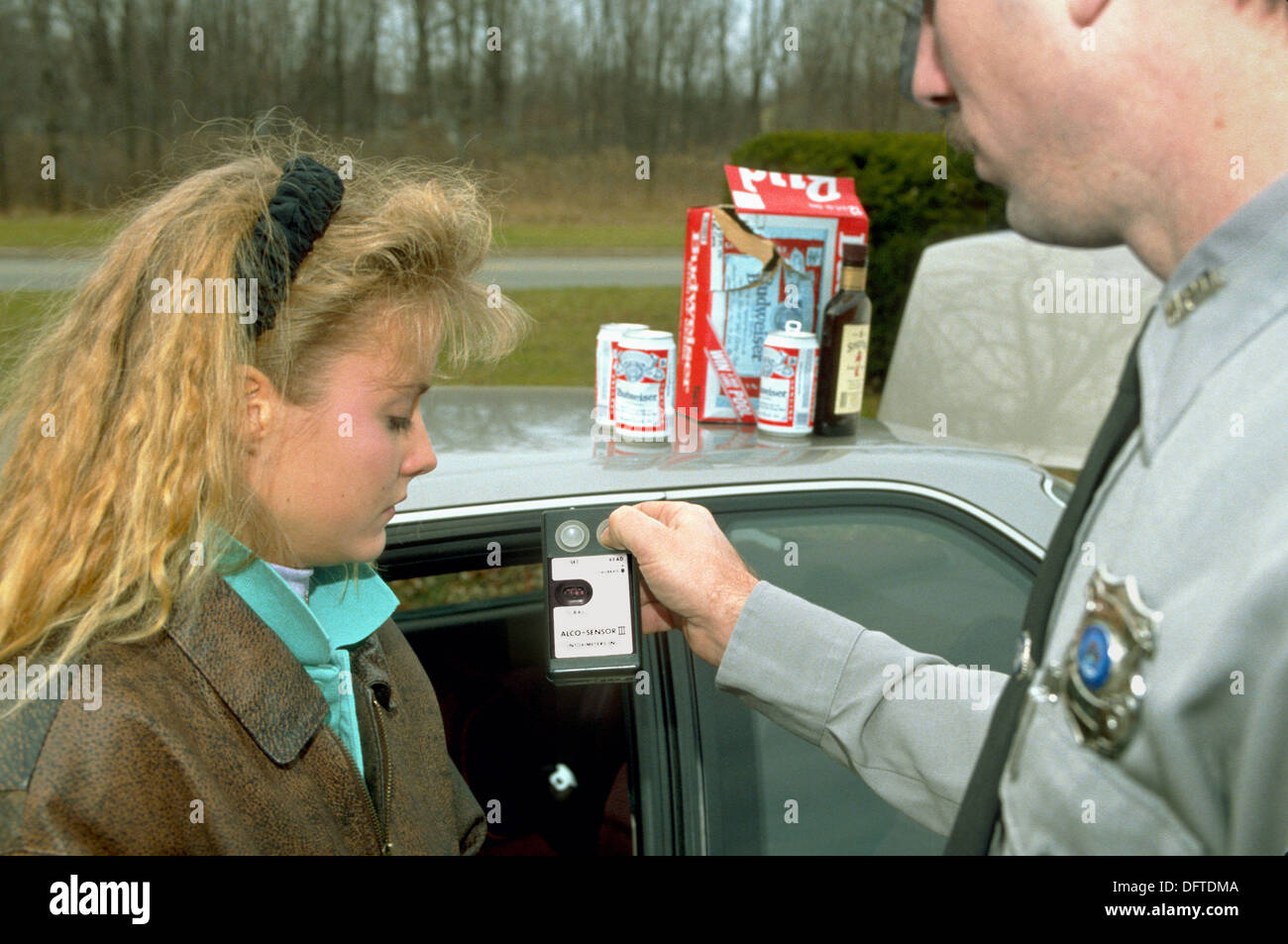 Police officer shows alcohol breath test results to teen female Stock