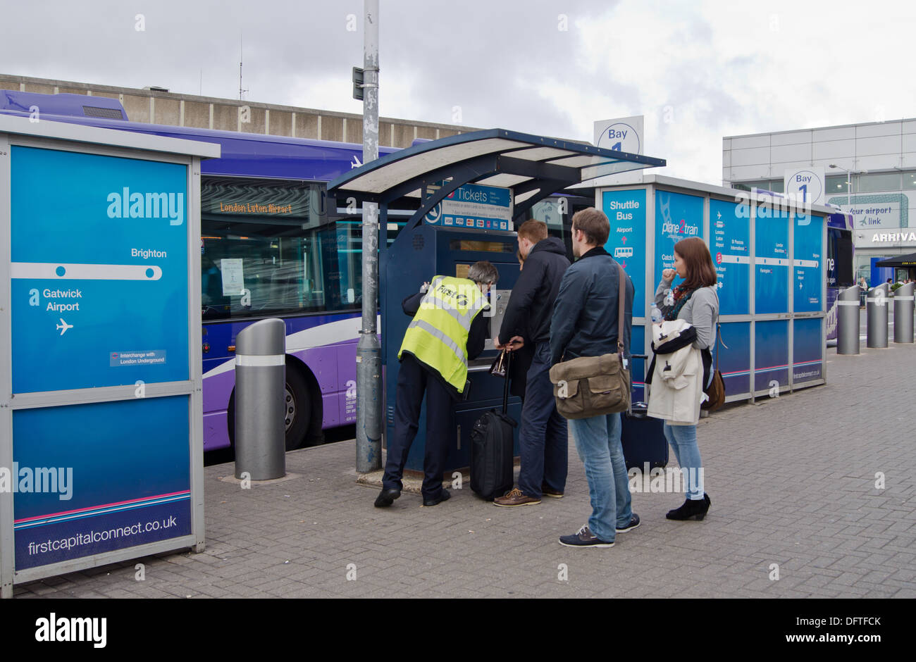 A man showing people how to buy tickets for the coach from a machine at Luton airport Stock Photo