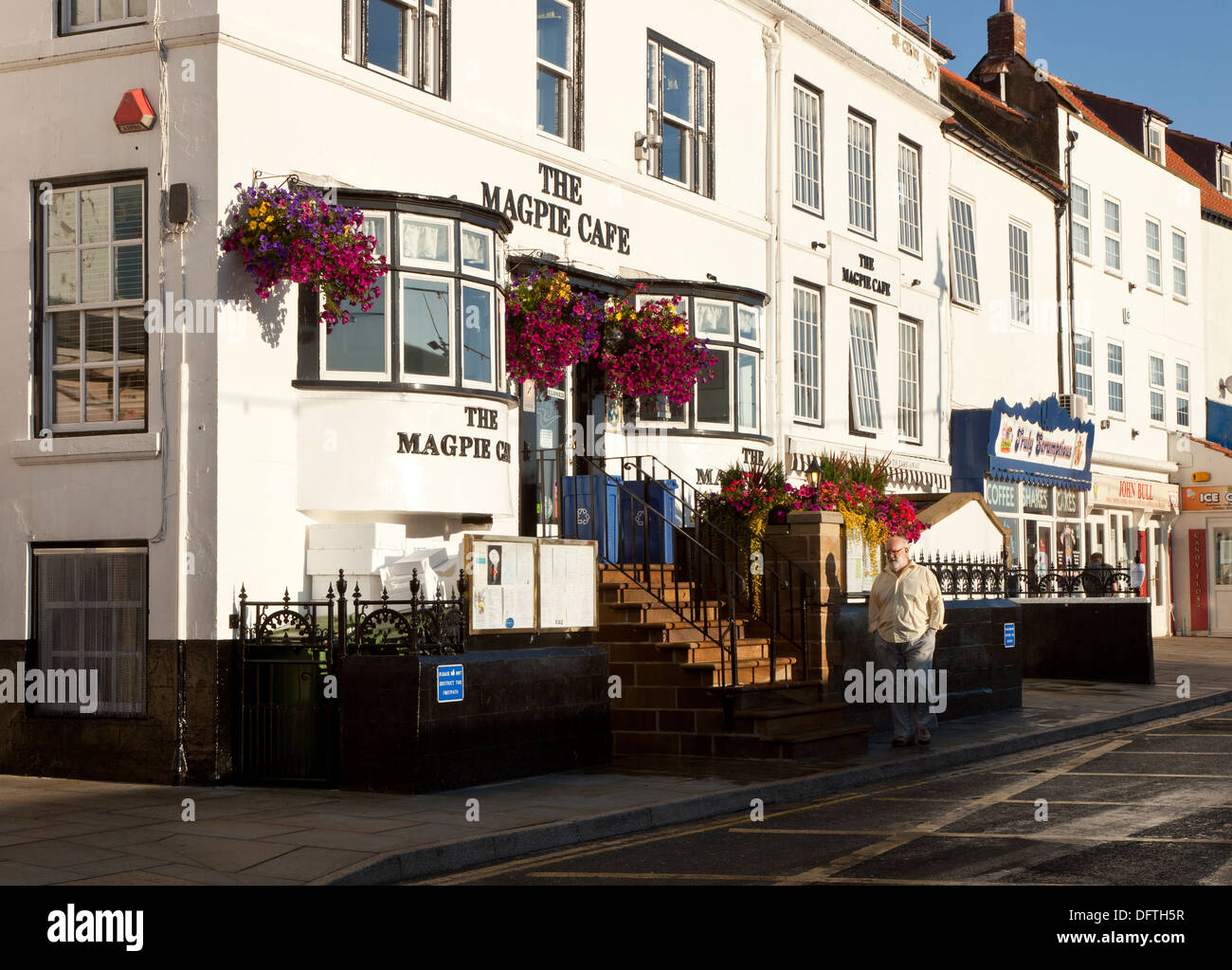 A man walking past the Magpie Cafe in Whitby in Yorkshire England Stock Photo