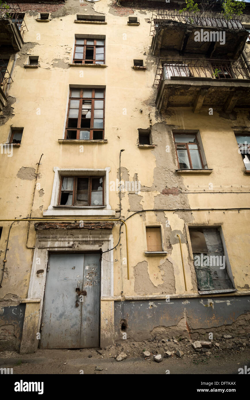 Abandoned apartment building with stained walls and broken windows