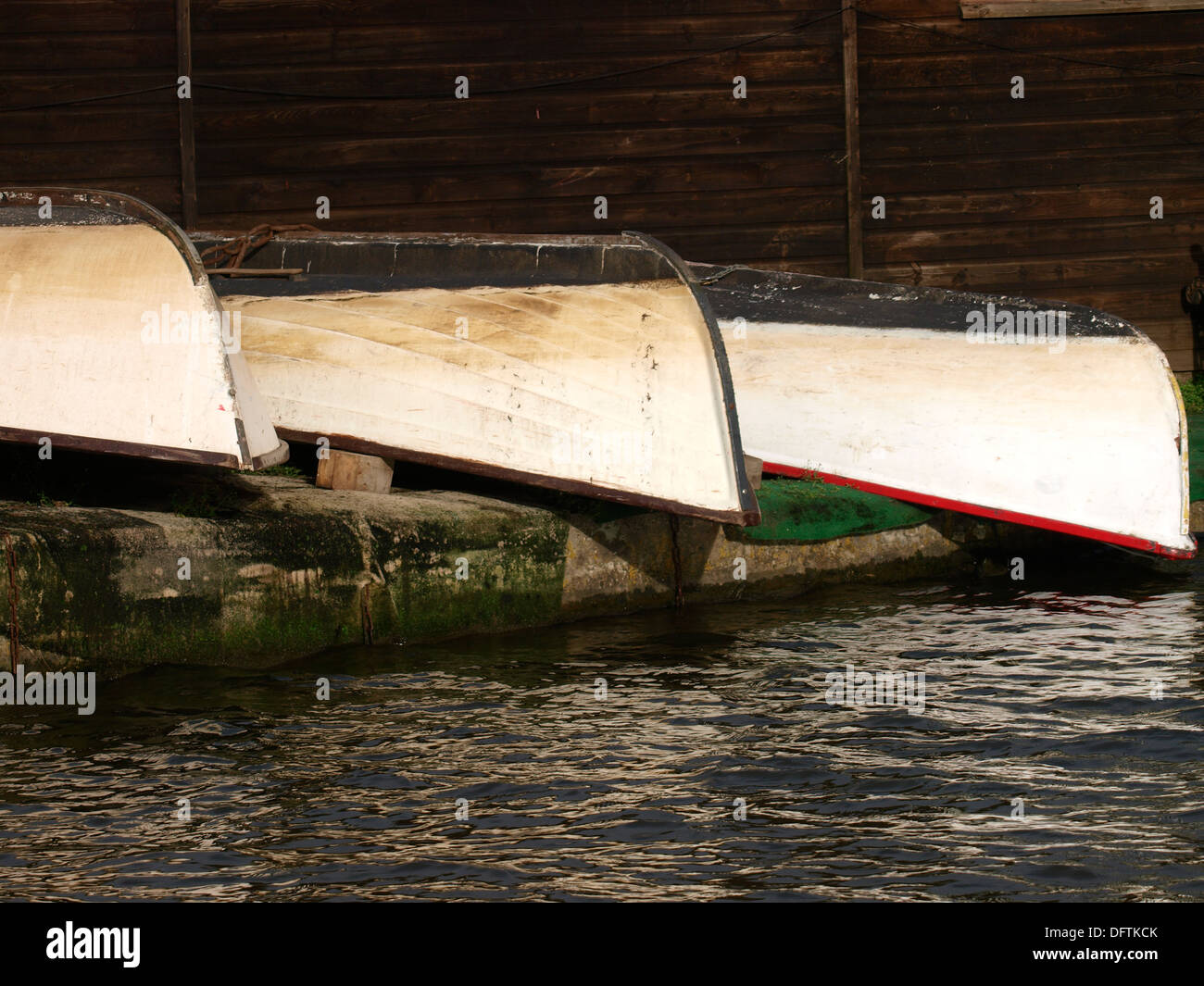 Three old rowing boats upside down on the side of a canal, Bude