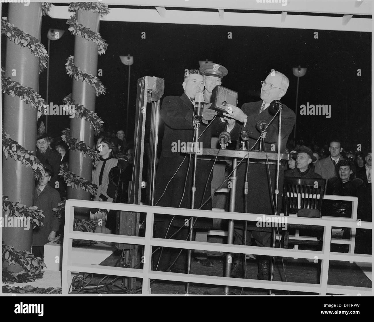A photograph captures President Truman pressing a button to light the National Community Christmas Tree at the White House, marking the start of the holiday season. Stock Photo