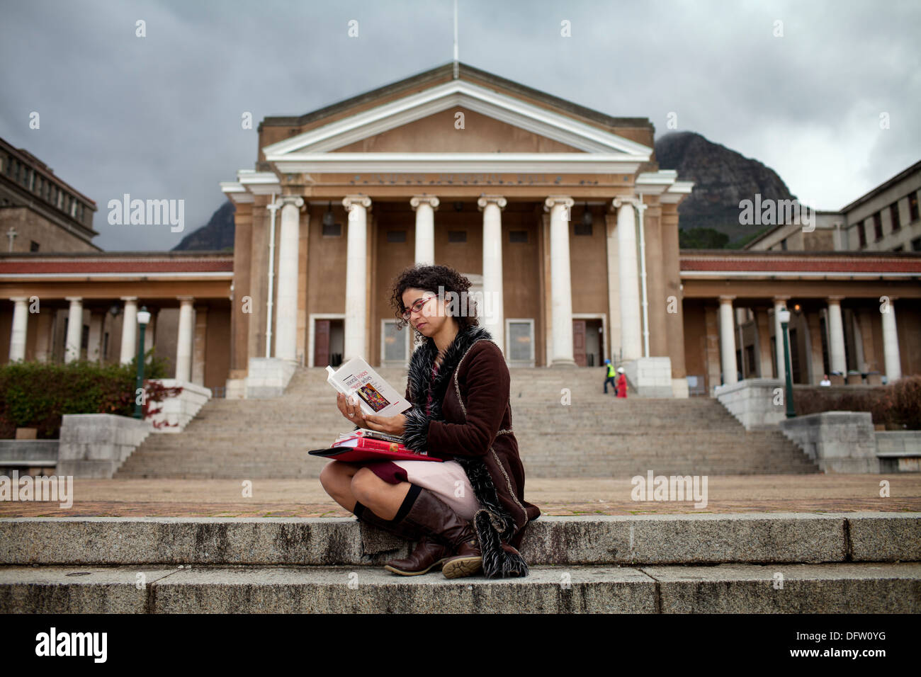 Nicole, postgraduate student, sits with books on her lap in front of Jameson Hall in Jammie Plaza at UCT Stock Photo