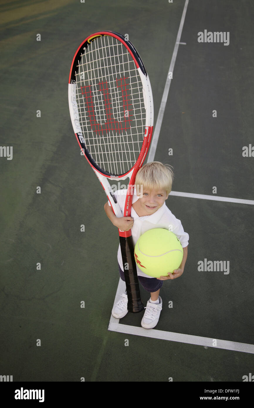Kid with a giant tennis ball and racket Stock Photo - Alamy