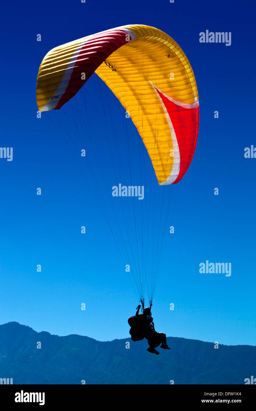 A lone hang glider soaring above the mountains Stock Photo