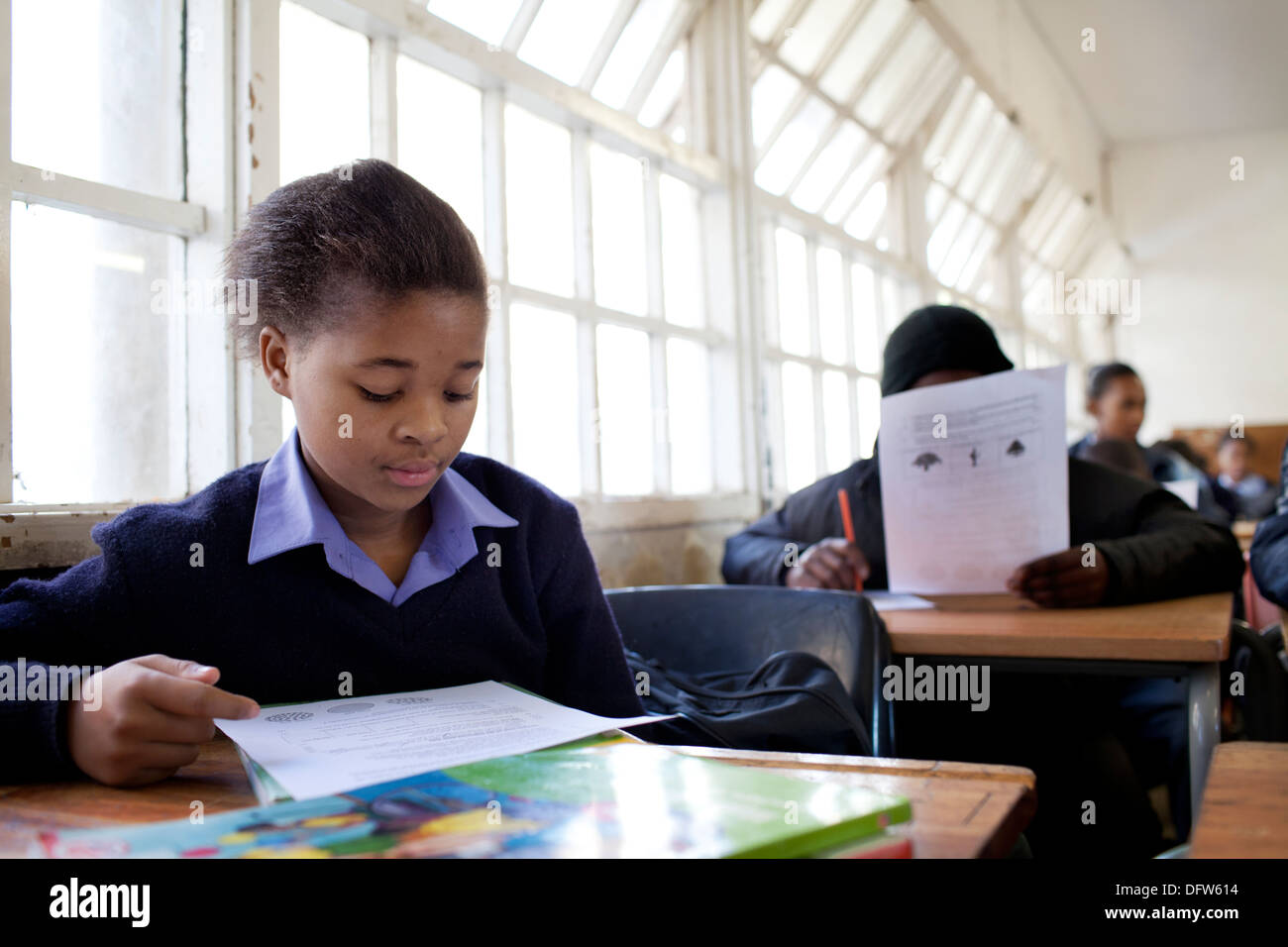 African schoolgirl reads a text book in class at Thandokhulli school, Mowbray, Cape Town. Stock Photo