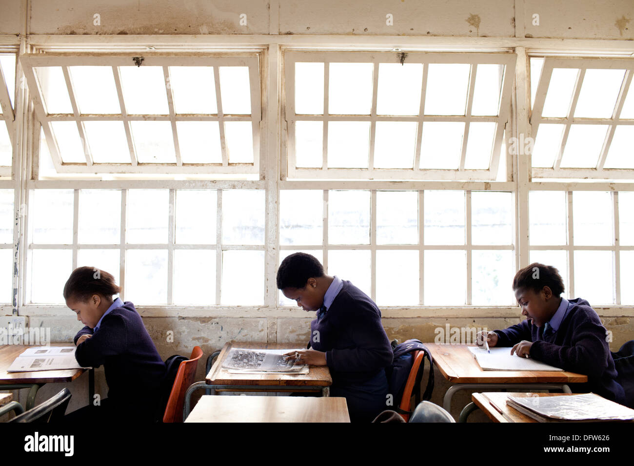 African schoolgirls read text books at their desks in class at Thandokhulli school, Mowbray, Cape Town. Stock Photo