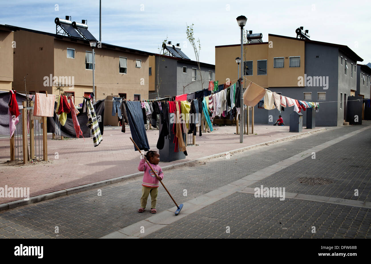 Cape Town South Africa - A young girl sweeps her street in a newly developed RDP housing project in Langa where all houses are Stock Photo