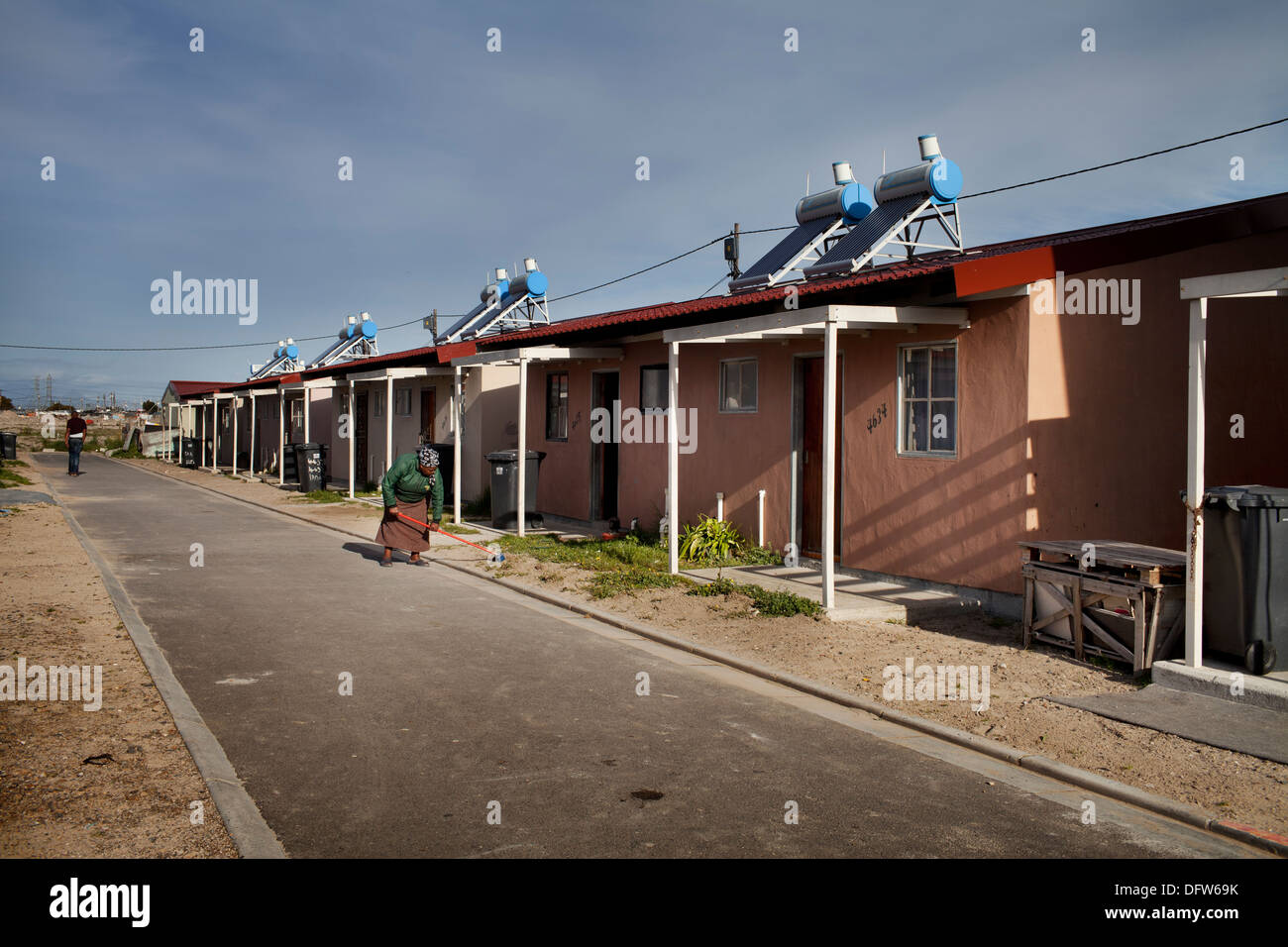 Cape Town South Africa - A woman sweeps her street in a newly developed RDP housing project in Langa where all houses are Stock Photo