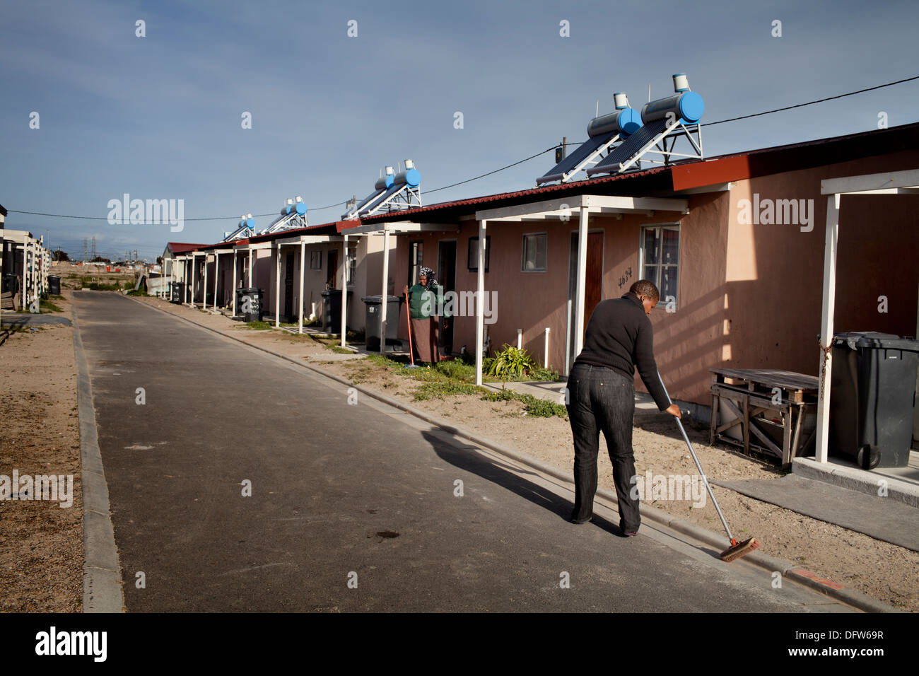 Cape Town South Africa - A woman sweeps her street in a newly developed RDP housing project in Langa where all houses are Stock Photo
