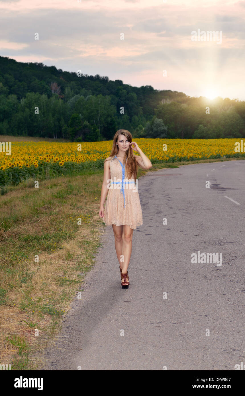 Alone young woman in short dress walking by country road Stock Photo ...
