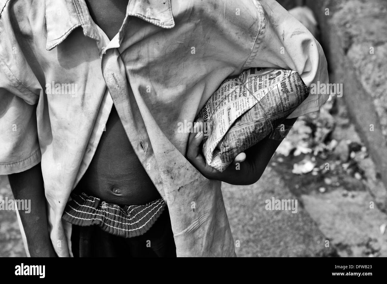 Indian lower caste boy with rice packet on an Indian street. Andhra Pradesh, India. Black and White selective focus Stock Photo