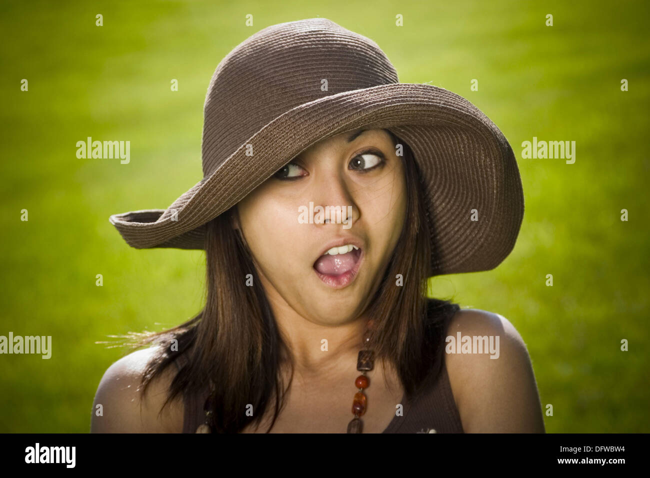 Young Spanish/Asian woman, wearing a hat, posing at a park Stock Photo Alamy