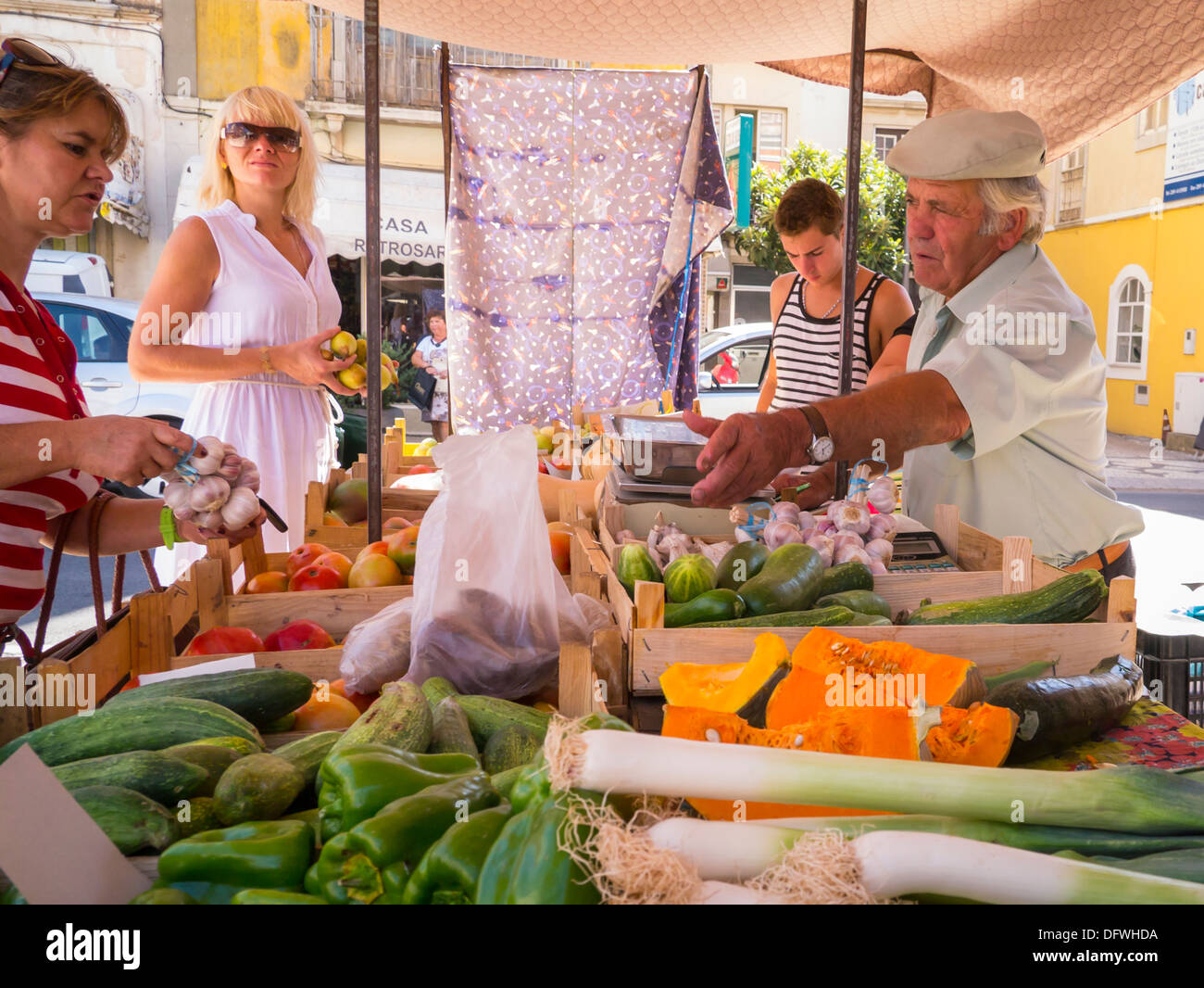 Portugal Algarve Loule market fruit veg vegetable stall leeks green peppers pumpkin courgettes garlic pears men women vendor customers sunshine sunny Stock Photo