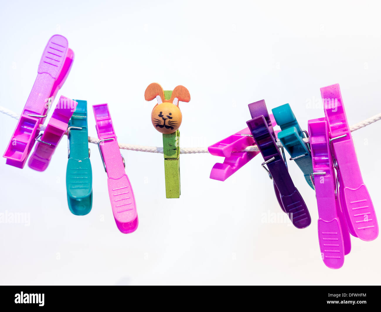 Colorful character plastic pegs on a line standing apart from the central lonely character Stock Photo